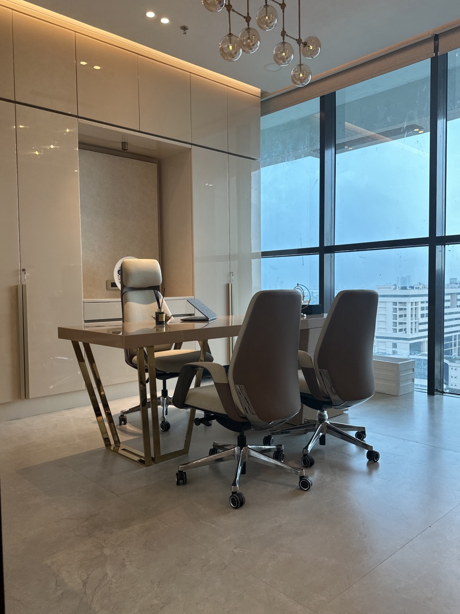 Custom executive desk and office chairs beside a city window
