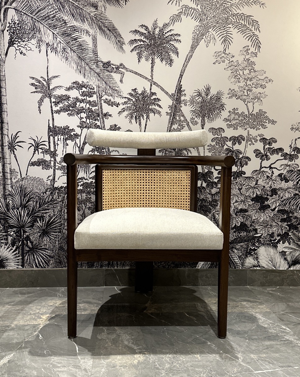 Wood and cane accent chair against a botanical wall